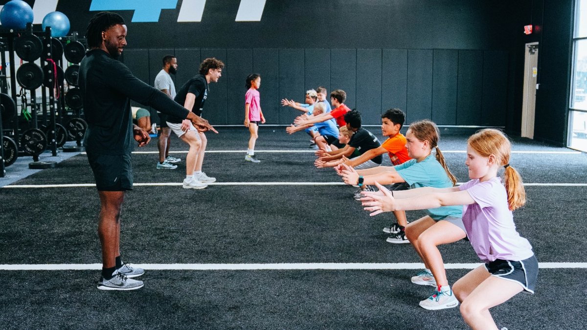 Trainers teaching a group session of young boys and girls exercises at the gym