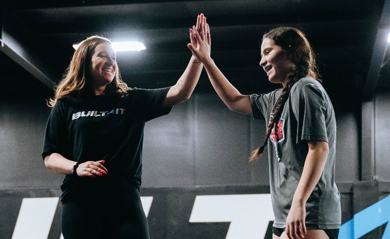 Trainer and young woman high fiving after a hard workout
