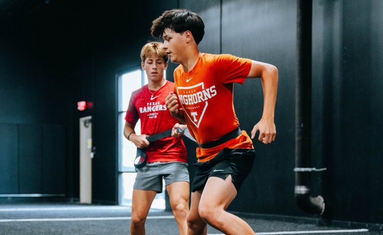 Two young men helping one another train at the gym