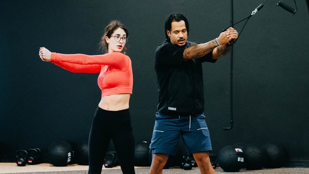 Women teaching man to use an exercise machine